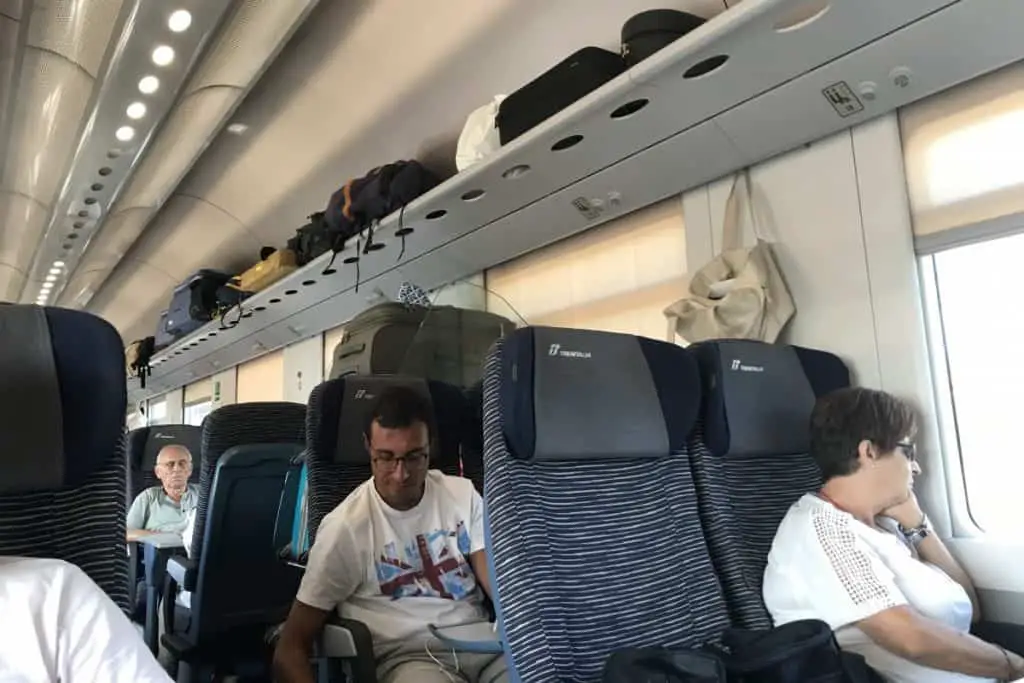 People sitting inside Trenitalia train with overhead racks for  luggage