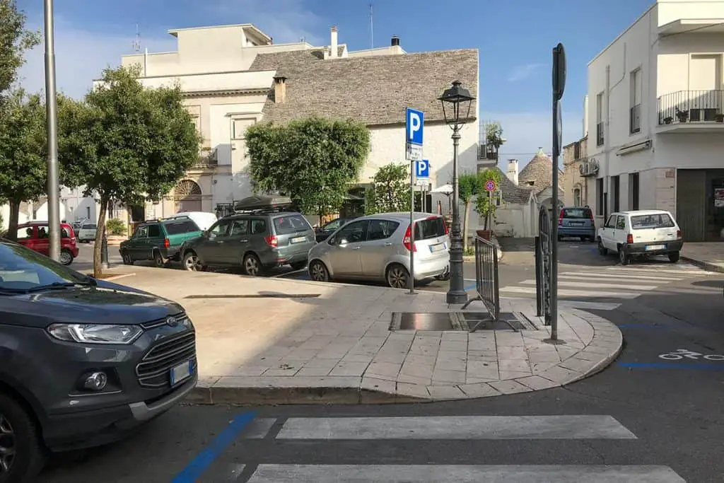 Street parking in Italy with pedestrian crossing and a blue parking sign in the middle
