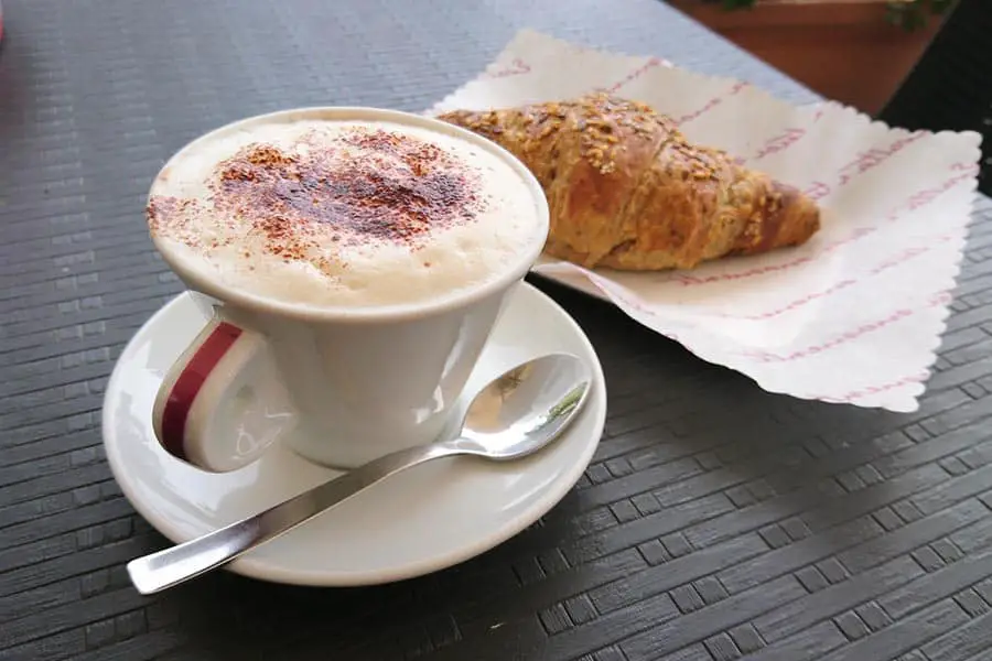 Cappuccino in a porcelain cup with a croissant