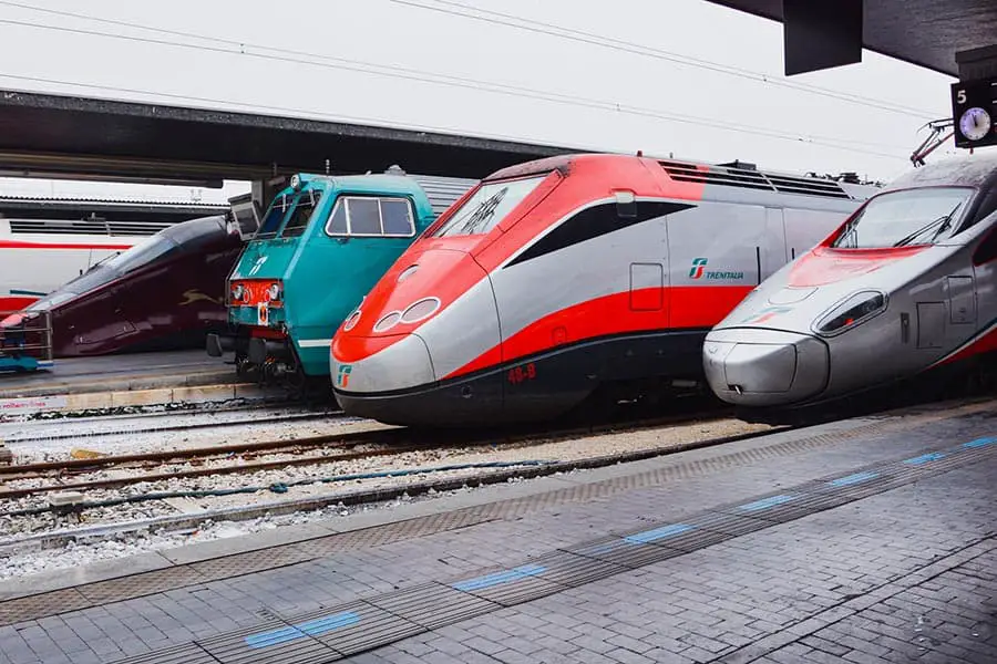 Red, silver, and green trains at an Italian train station